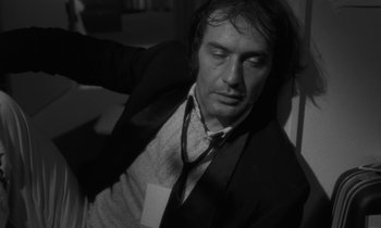 Movie still from “The State of Things” (1982), directed by Wim Wenders – Black and white photograph of a man in a suit and tie; Close Up shot, Low angle