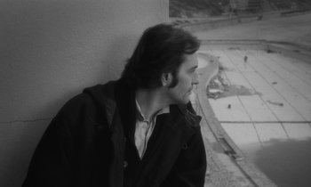 Movie still from “The State of Things” (1982), directed by Wim Wenders – Black and white photograph of a man leaning against a wall; Close Up shot, High angle