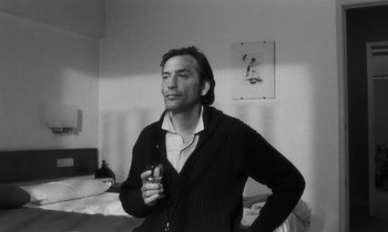 Movie still from “The State of Things” (1982), directed by Wim Wenders – A black and white photo of a man holding a cell phone; Medium shot, Low angle