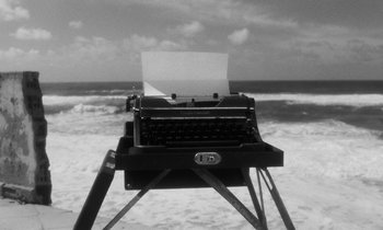 Movie still from “The State of Things” (1982), directed by Wim Wenders – An old fashioned type writer sitting in front of the ocean; Wide shot, High angle
