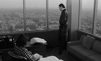 Movie still from “The State of Things” (1982), directed by Wim Wenders – A black and white photo of a man looking out of a window; Medium shot, Over the shoulder angle