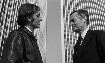 Movie still from “The State of Things” (1982), directed by Wim Wenders – Two men in business suits facing one another; Medium shot, Low angle