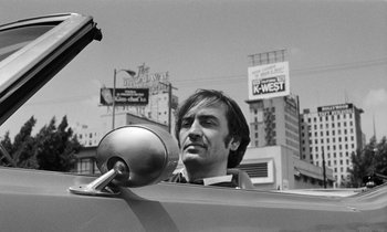 Movie still from “The State of Things” (1982), directed by Wim Wenders – A black and white photo of a man in the back of a car; Close Up shot, Low angle