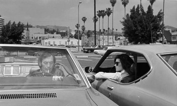 Movie still from “The State of Things” (1982), directed by Wim Wenders – A woman is driving a car while smoking a cigarette; Medium shot, Over the shoulder angle
