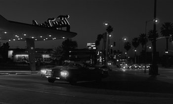 Movie still from “The State of Things” (1982), directed by Wim Wenders – A black and white photo of cars driving down a street; Extreme Wide shot, Low angle
