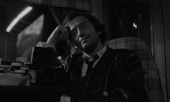 Movie still from “The State of Things” (1982), directed by Wim Wenders – A black and white photo of a man in a suit and tie; Close Up shot, Over the shoulder angle