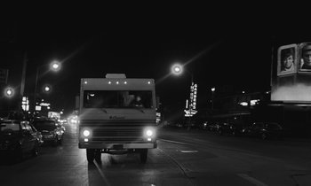 Movie still from “The State of Things” (1982), directed by Wim Wenders – A black - and - white photo of a bus on the street; Wide shot, Low angle
