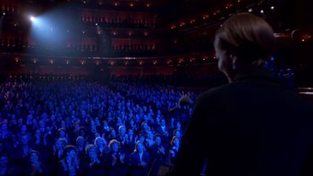 Movie still from “The Stepford Wives” (2004), directed by Frank Oz – A crowd of people sitting in a large auditorium; Extreme Wide shot, Over the shoulder angle
