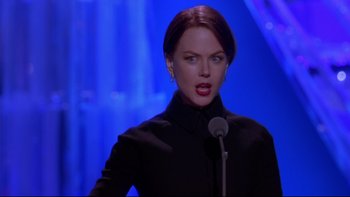 Movie still from “The Stepford Wives” (2004), directed by Frank Oz – A woman standing in front of a microphone on a stage; Medium shot, Low angle