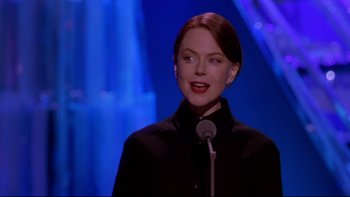 Movie still from “The Stepford Wives” (2004), directed by Frank Oz – A woman standing in front of a microphone on a stage; Close Up shot, Low angle
