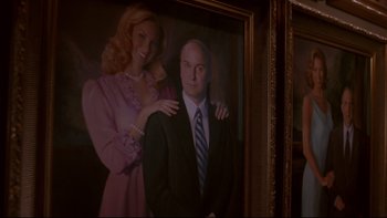 Movie still from “The Stepford Wives” (2004), directed by Frank Oz – A man and a woman are posed in front of a painting; Medium shot, Low angle