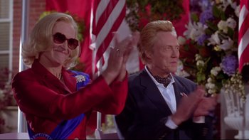 Movie still from “The Stepford Wives” (2004), directed by Frank Oz – Two people clapping in front of american flags; Medium shot, Low angle
