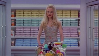 Movie still from “The Stepford Wives” (2004), directed by Frank Oz – A woman standing next to a shopping cart filled with groceries; Medium shot, Low angle