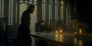 Movie still from “House of the Dragon” (2022), created by George R.R. Martin – A group of people sitting around a table with candles; Medium shot, Low angle