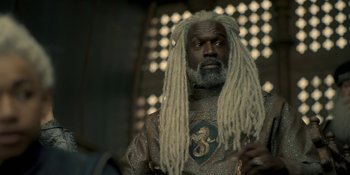 Movie still from “House of the Dragon” (2022), created by George R.R. Martin – A man with dreads and a beard is wearing a suit; Close Up shot, Low angle