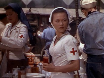 Movie still from “The Story of Dr. Wassell” (1944), directed by Cecil B. DeMille – An asian nurse holding a bottle of medicine; Medium shot, Low angle