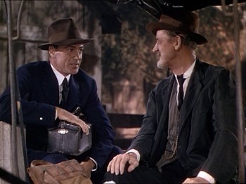 Movie still from “The Story of Dr. Wassell” (1944), directed by Cecil B. DeMille – Two men sitting next to each other on the ground; Medium shot, Over the shoulder angle