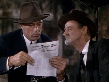 Movie still from “The Story of Dr. Wassell” (1944), directed by Cecil B. DeMille – Two men are looking at a newspaper together; Medium shot, Over the shoulder angle