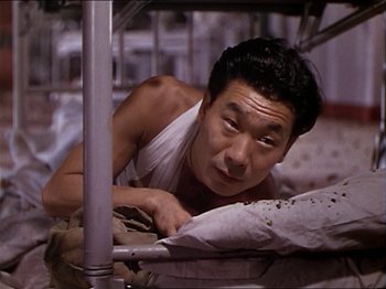 Movie still from “The Story of Dr. Wassell” (1944), directed by Cecil B. DeMille – A man laying on a bed looking at the camera; Close Up shot, High angle