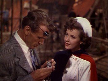 Movie still from “The Story of Dr. Wassell” (1944), directed by Cecil B. DeMille – A man and a woman looking at a camera; Medium shot, Over the shoulder angle