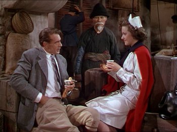 Movie still from “The Story of Dr. Wassell” (1944), directed by Cecil B. DeMille – A man and a woman sitting next to each other; Medium shot, High angle