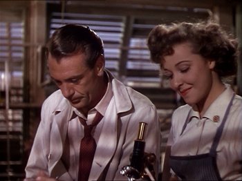Movie still from “The Story of Dr. Wassell” (1944), directed by Cecil B. DeMille – A man and a woman sitting next to each other at a table; Medium shot, High angle