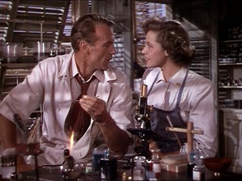 Movie still from “The Story of Dr. Wassell” (1944), directed by Cecil B. DeMille – A man and a woman sitting at a table; Medium shot, Low angle