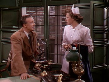 Movie still from “The Story of Dr. Wassell” (1944), directed by Cecil B. DeMille – A man and a woman talking to each other in front of a table; Medium shot, Over the shoulder angle