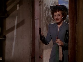 Movie still from “The Story of Dr. Wassell” (1944), directed by Cecil B. DeMille – A woman wearing a hat and holding a glass of wine; Medium shot, Low angle