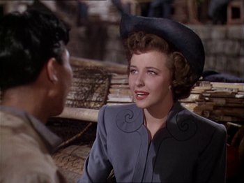 Movie still from “The Story of Dr. Wassell” (1944), directed by Cecil B. DeMille – A woman wearing a cowboy hat talking to a man; Medium shot, Over the shoulder angle