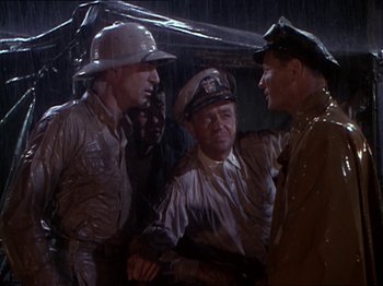 Movie still from “The Story of Dr. Wassell” (1944), directed by Cecil B. DeMille – A group of men standing next to each other in the rain; Medium shot, High angle