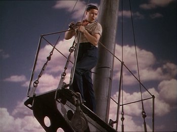 Movie still from “The Story of Dr. Wassell” (1944), directed by Cecil B. DeMille – A man standing on top of a metal pole; Medium shot, Low angle
