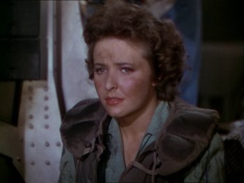 Movie still from “The Story of Dr. Wassell” (1944), directed by Cecil B. DeMille – A woman in a green shirt and brown jacket; Close Up shot, Over the shoulder angle