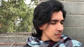Movie still from “The Story of Film: A New Generation” (2021), directed by Mark Cousins – A man with long black hair wearing a scarf; Close Up shot, Low angle