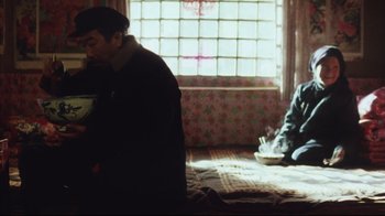 Movie still from “The Story of Qiu Ju” (1992), directed by Yimou Zhang – A man sitting on a bed next to another man; Medium shot, Over the shoulder angle