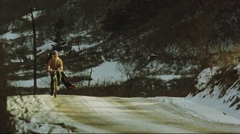 Movie still from “The Story of Qiu Ju” (1992), directed by Yimou Zhang – A man riding a bike on top of a snow covered slope; Extreme Wide shot, High angle