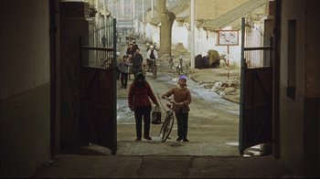 Movie still from “The Story of Qiu Ju” (1992), directed by Yimou Zhang – Two women walking down a street with a bicycle; Extreme Wide shot, High angle