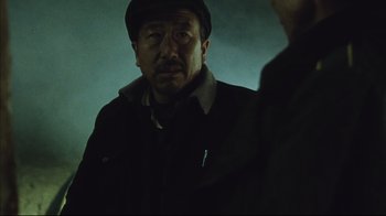 Movie still from “The Story of Qiu Ju” (1992), directed by Yimou Zhang – A man wearing a hat is looking at the camera; Close Up shot, Low angle