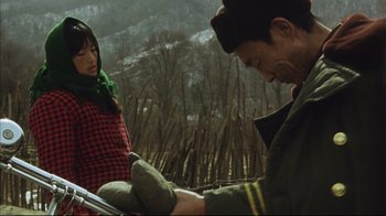 Movie still from “The Story of Qiu Ju” (1992), directed by Yimou Zhang – A man and a woman are looking at something on the ground; Medium shot, Low angle