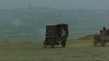Movie still from “The Story of Qiu Ju” (1992), directed by Yimou Zhang – A man riding a cart on top of a dirt field; Extreme Wide shot, High angle