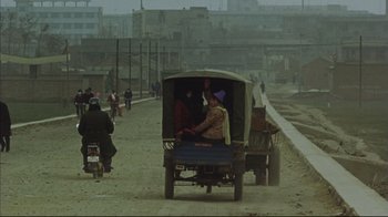Movie still from “The Story of Qiu Ju” (1992), directed by Yimou Zhang – A group of people riding on the back of a truck; Wide shot, High angle