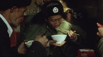 Movie still from “The Story of Qiu Ju” (1992), directed by Yimou Zhang – A man eating a bowl of food with chopsticks; Medium shot, High angle