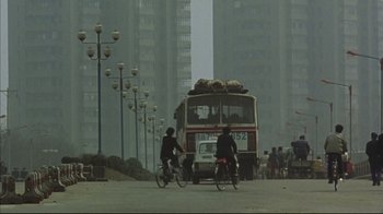 Movie still from “The Story of Qiu Ju” (1992), directed by Yimou Zhang – Two people on bikes in front of a bus; Extreme Wide shot, Low angle