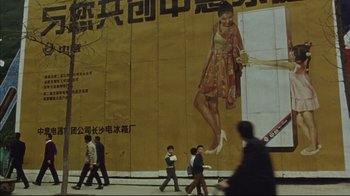 Movie still from “The Story of Qiu Ju” (1992), directed by Yimou Zhang – A group of people walking down a sidewalk next to an advertisement; Extreme Wide shot, Low angle