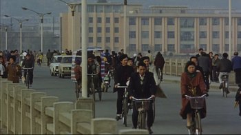 Movie still from “The Story of Qiu Ju” (1992), directed by Yimou Zhang – A group of people riding bikes down a street; Wide shot, High angle