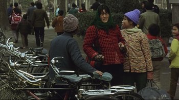 Movie still from “The Story of Qiu Ju” (1992), directed by Yimou Zhang – A group of people standing next to parked motorcycles; Medium shot, High angle