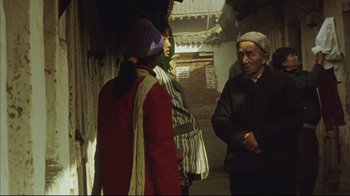 Movie still from “The Story of Qiu Ju” (1992), directed by Yimou Zhang – A group of people standing around in a room; Medium shot, Over the shoulder angle