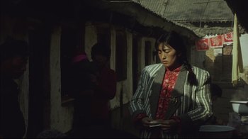Movie still from “The Story of Qiu Ju” (1992), directed by Yimou Zhang – A woman standing next to another woman holding a cell phone; Medium shot, High angle