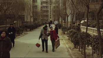 Movie still from “The Story of Qiu Ju” (1992), directed by Yimou Zhang – Two women walking down a street holding hands; Wide shot, High angle