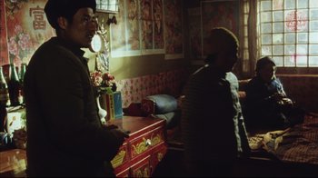 Movie still from “The Story of Qiu Ju” (1992), directed by Yimou Zhang – Two men standing next to each other in a living room; Medium shot, Low angle